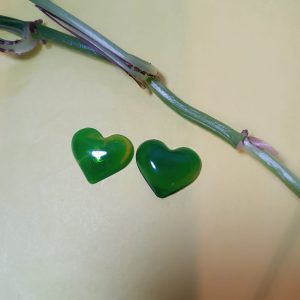 Par de pendientes de resina epoxi con forma de corazón en color verde esmeralda. El color es brillante y translúcido.