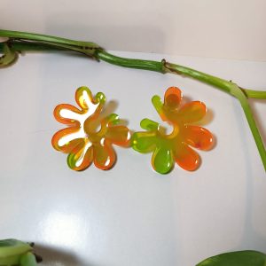 Par de pendientes de resina epoxi de forma ovalada con un acabado nacarado que refleja un tono rosado y brillo iridiscente.
