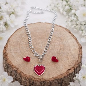 Set Latido Carmesí con collar y pendientes de corazón rojo sobre base de madera natural.
