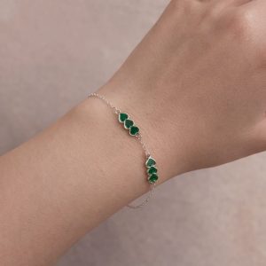 Pulsera Trébol Esmeralda con corazones verdes puesta en la muñeca.